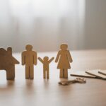 Wooden family figures and house with keys on table.
